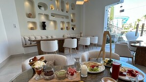 Een eetgedeelte met een ronde glazen tafel, diverse gerechten en een zithoek met banken en stoelen.