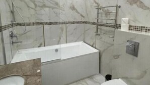 A bathroom with a bathtub, a toilet, and a shower area. - Villa ACAEM #4 (Chișinău)