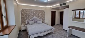 Une chambre à coucher avec un lit, des tables de chevet, une commode et une fenêtre.