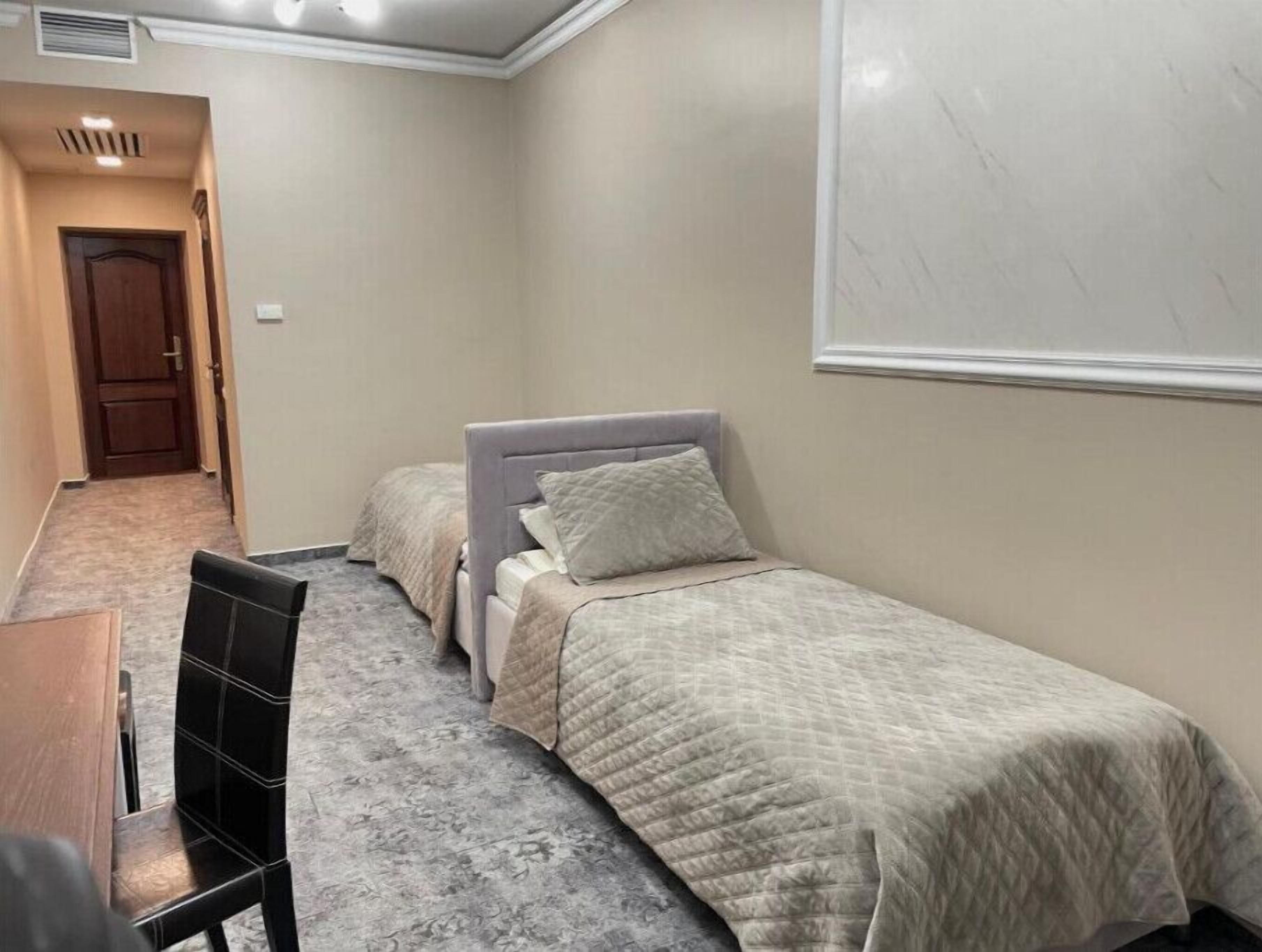 A bedroom with two single beds, a wooden desk, and a chair.