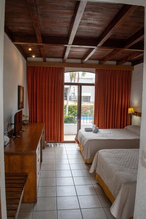 Habitació d'hotel amb sostre de fusta, dos llits, una taula de treball i vista cap a l'exterior.
