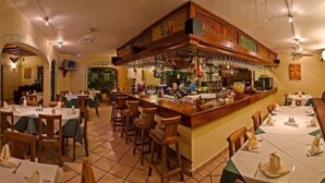 A restaurant with a bar area, multiple tables, and chairs. - Hotel Pez Vela (Manzanillo)
