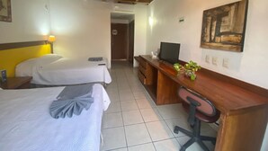 A hotel room with two beds, a desk with a computer, a chair, and a plant. - Hotel Pez Vela (Manzanillo)