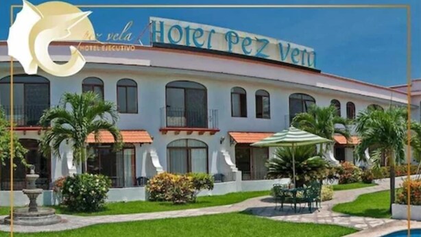A hotel with a swimming pool, a well-maintained lawn, and a clear sky. - Hotel Pez Vela (Manzanillo)