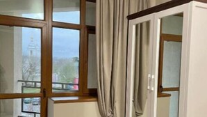 Ein Zimmer mit einem großen Fenster, einem Kleiderschrank und Blick auf ein Gebäude.