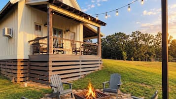 A house with a covered porch, outdoor seating, and a fire pit.