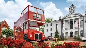 A red double-decker bus with the number 22, parked in front of a white building with a clock tower.