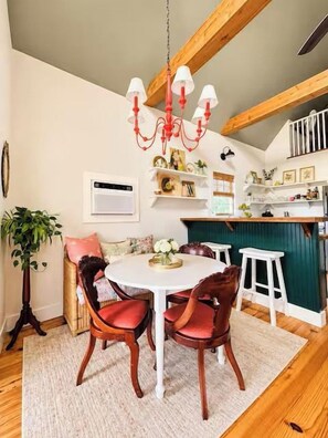 A dining area with a round table, wooden chairs, a chandelier, and a kitchen in the background. - The Cottage, Firepit+ Animals, VelvetDitchVillas (Oxford)