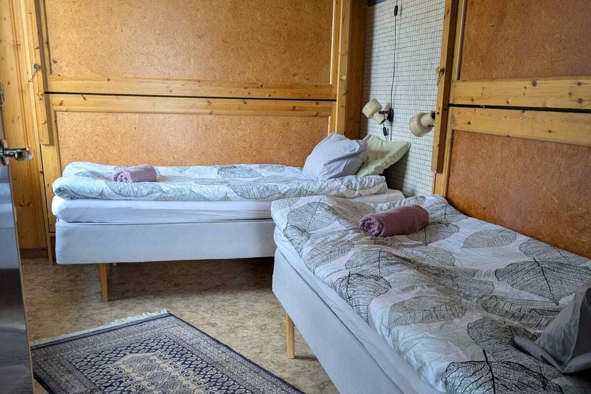 Una habitación con dos camas de madera, un tapete estampado y un armario de madera.