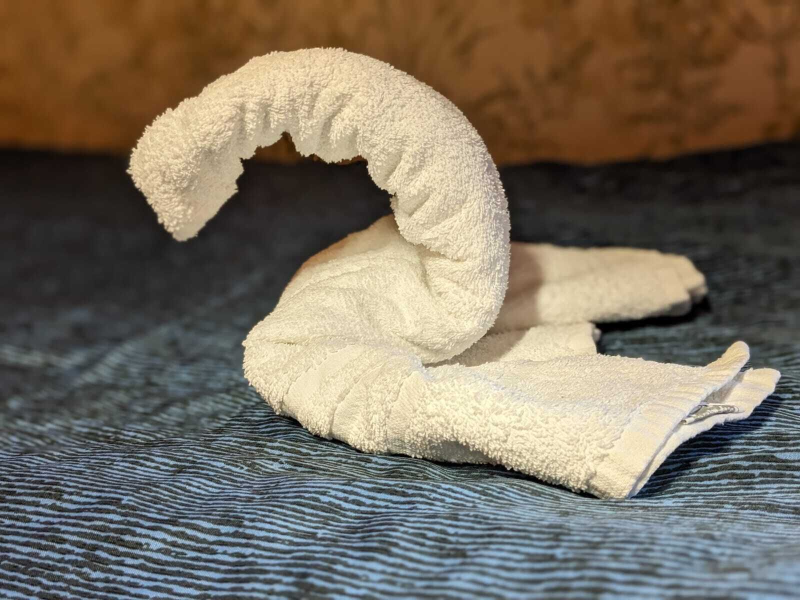A towel shaped like a swan on a textured fabric surface.