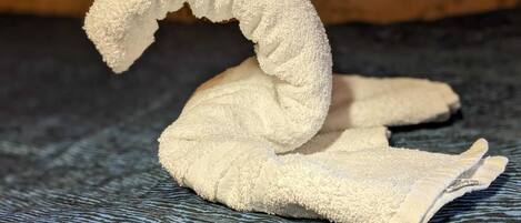 A towel shaped like a swan on a textured fabric surface.