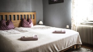 A neatly made bed with a wooden headboard, two pillows, and folded towels. - Hotel Nederhögen Vildmarkscenter (Rätan)