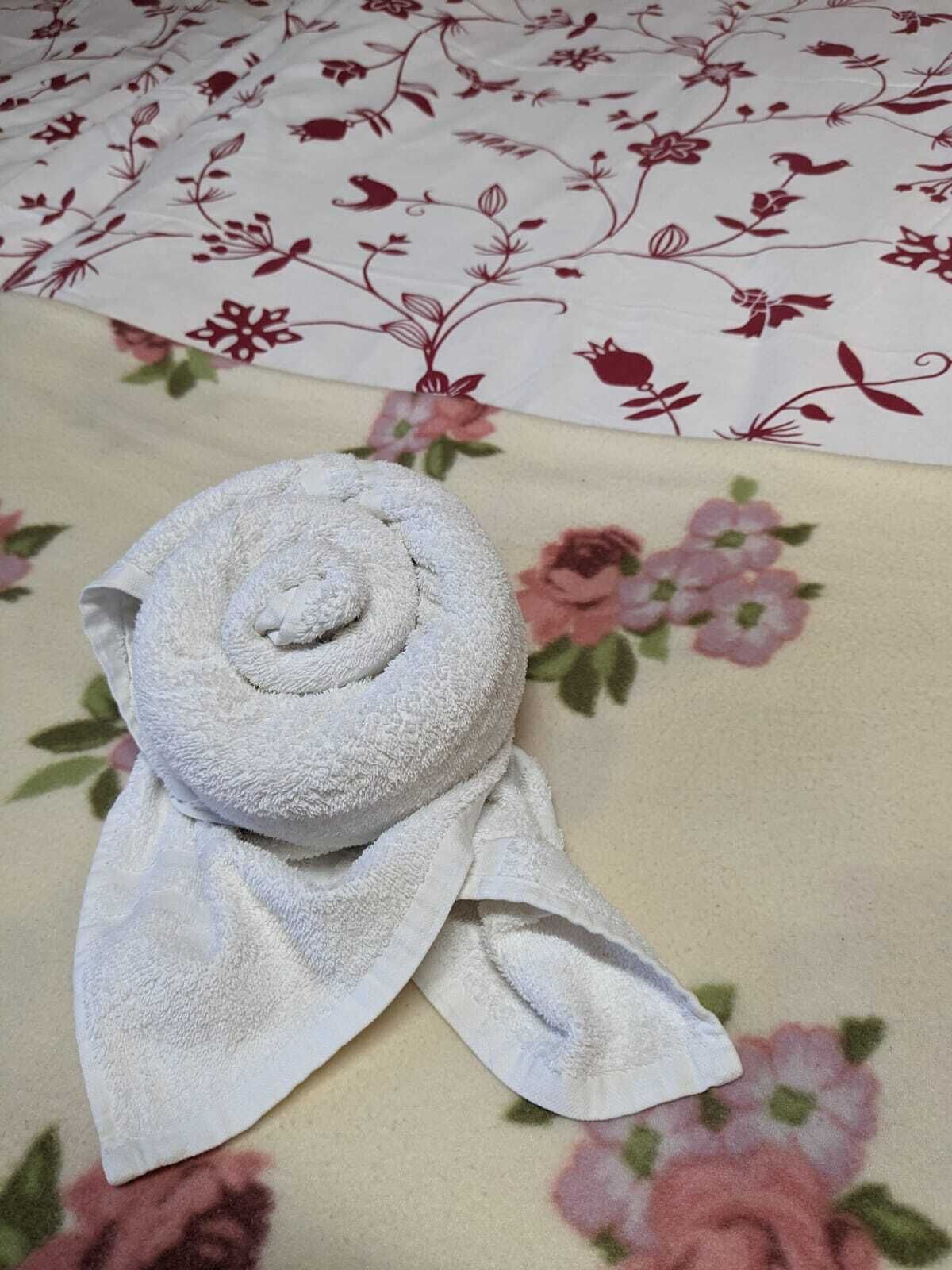 Et pænt foldet hvidt håndklæde på et blomstret sengetæppe.