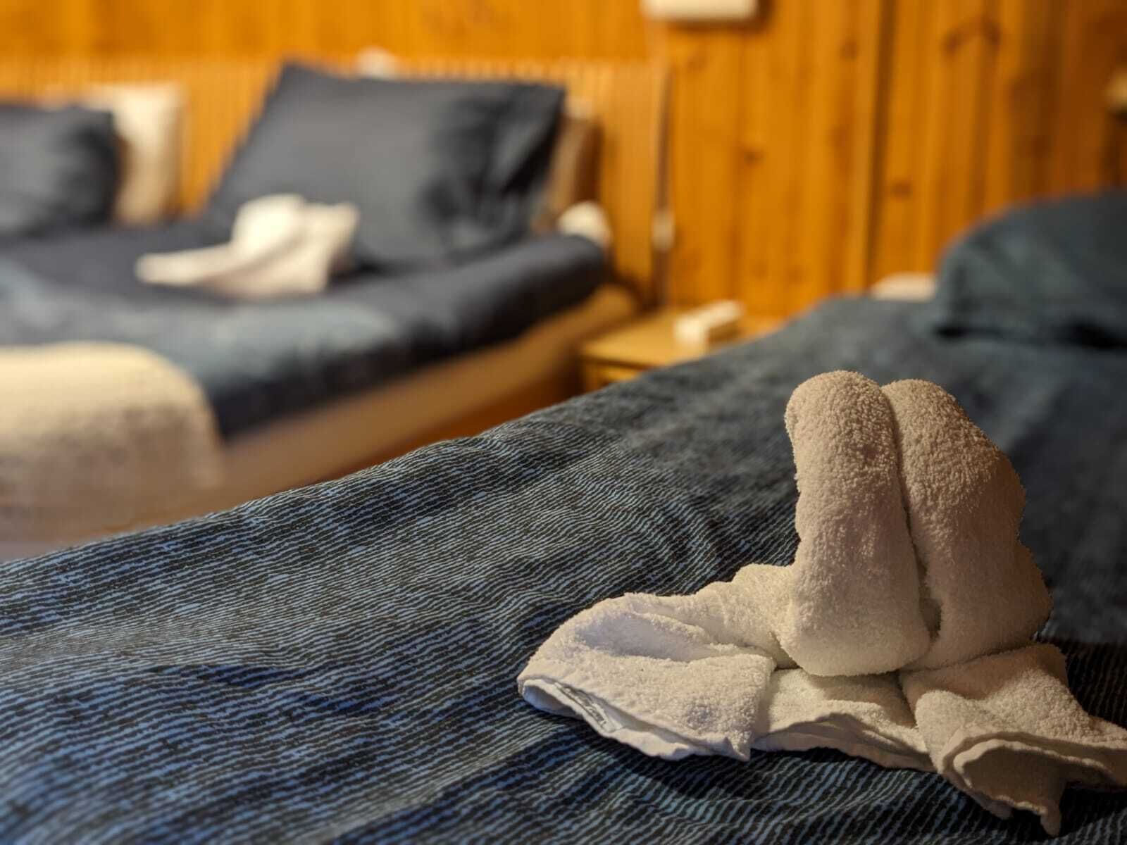 A hotel room with two beds, wooden walls, and a visible nightstand.