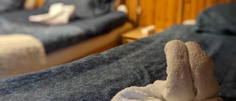 A hotel room with two beds, wooden walls, and a visible nightstand.