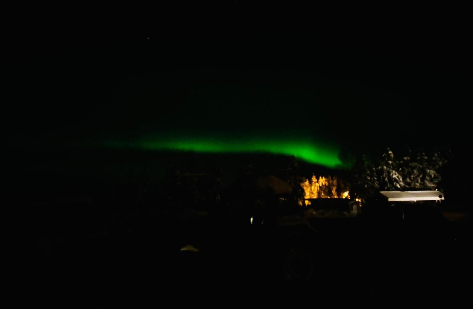 A dark scene with a green light in the sky.
