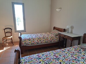 Ein Schlafzimmer mit Bett, Stuhl, Nachttisch und Fenster.
