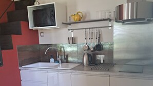 A modern kitchen with white cabinets, a stainless steel sink, a microwave, and a range hood. - Country house in a beautiful natural setting, in the heart of the Gard department (Sauzet)
