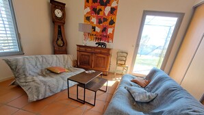 A living room with two sofas, a coffee table, a clock, and a wall poster. - Country house in a beautiful natural setting, in the heart of the Gard department (Sauzet)