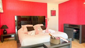 Un dormitorio con cama, mesita de noche, lámpara, cómoda y una flor decorativa en la pared.