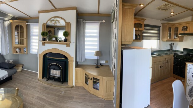A spacious living room with a fireplace, a kitchen with wooden cabinets, and a dining area.