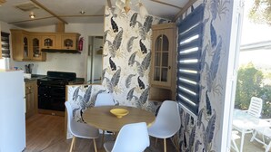 A compact kitchen with wooden cabinets, a stove, and a dining area with a round table and chairs.