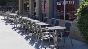 A restaurant with outdoor seating, a signboard, and a concrete exterior wall.