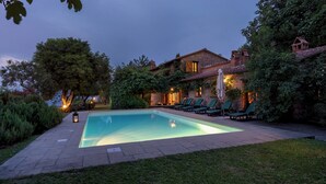 A swimming pool with lounge chairs and a stone building with a tiled roof. - Podere Belvedere 6, Emma Villas (Montevarchi)