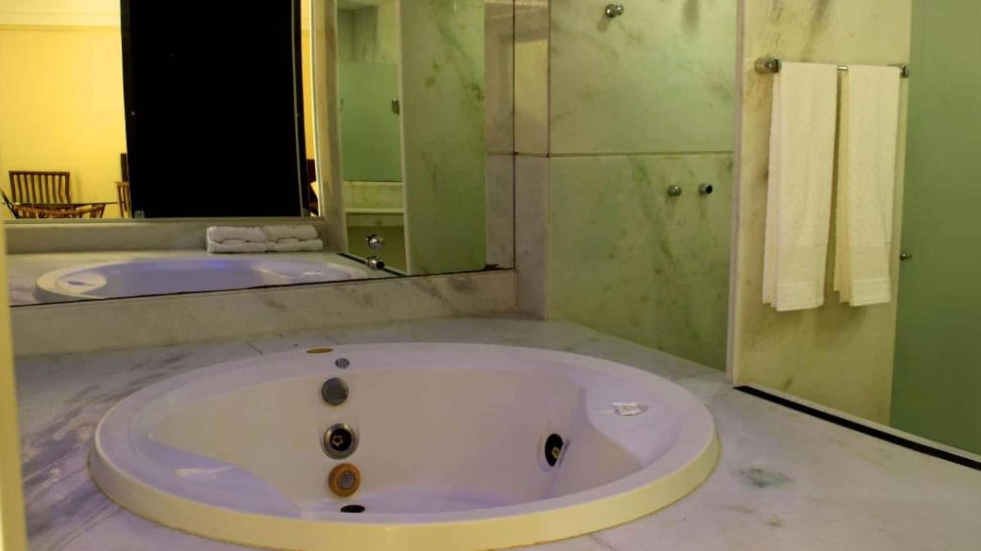 Un baño con una bañera grande, un espejo y un perchero para toallas.
