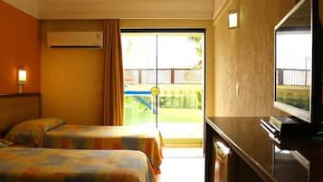 Habitación de hotel con dos camas, televisión, aire acondicionado y puerta corrediza de vidrio que da a un balcón.