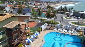 A hotel with a swimming pool, beach view, and a bridge in the background.