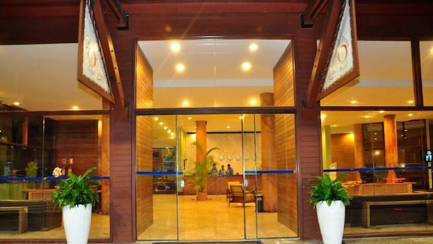 A hotel entrance with a reception desk, glass doors, and potted plants.