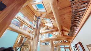 Een houten interieur met een hoge plafond en dakramen.