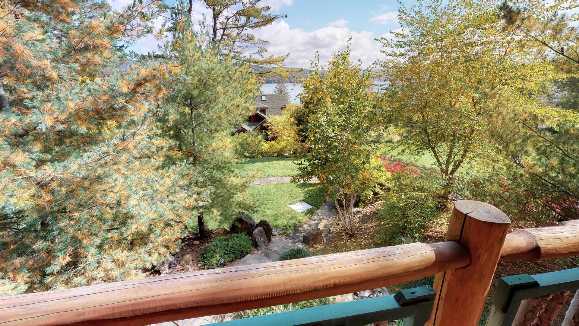 Una terraza de madera con vistas a un jardín y una casa al fondo.