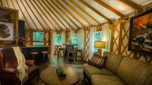 Un interior acogedor con techo alto, vigas de madera, una zona de bar, asientos y un cuadro de un paisaje.
