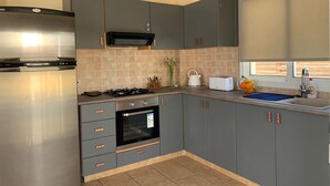 Eine moderne Küche mit grauen Schränken, einem Edelstahlkühlschrank, einem eingebauten Backofen und einem Gasherd.