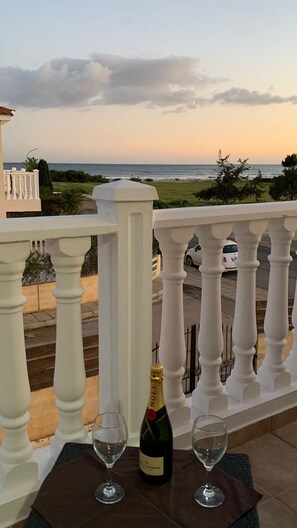 A balcony with a view of the sea, a bottle of champagne, and two glasses on a table. - Sunset Villa in Ayia Thekla next to the sea (Ayia Thekla)