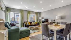 Een moderne woonkamer met een bank, een salontafel en een eethoek met stoelen en een tafel.