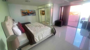 A modern hotel room with a large bed, a glass door leading to a balcony, and a painting on the wall. - Beautiful penthouse in Boca del Mar Residence (Boca Chica)