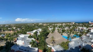 A coastal town with a view of the sea, buildings with red roofs, and a prominent thatched-roof structure. - Beautiful penthouse in Boca del Mar Residence (Boca Chica)