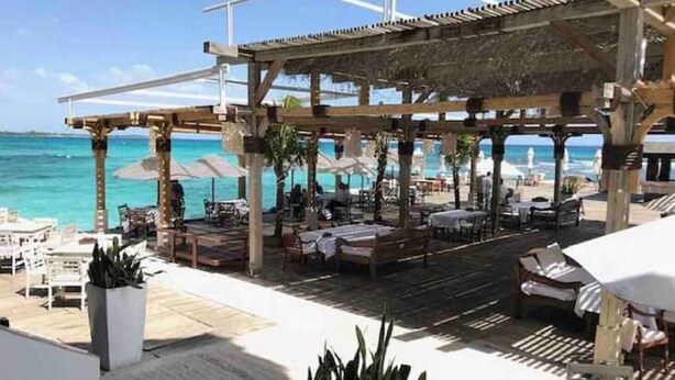 An outdoor seating area with tables and chairs, umbrellas, and a view of the ocean. - Beautiful penthouse in Boca del Mar Residence (Boca Chica)