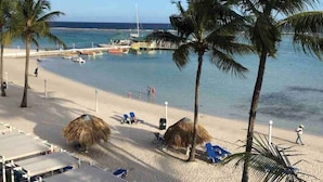 A beach with palm trees, a pier, and a few people. - Beautiful penthouse in Boca del Mar Residence (Boca Chica)