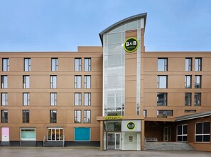 A B&B hotel with a modern design, featuring a reception area and multiple floors with large windows.