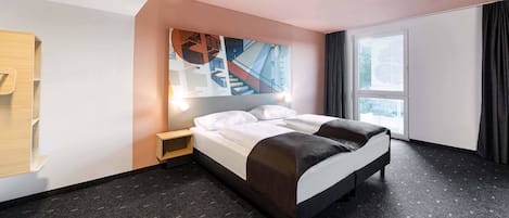 A modern hotel room with a large bed, a nightstand, a wall-mounted TV, and a window with curtains.