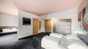 A hotel room with a bed, a desk, a mirror, and a wardrobe.