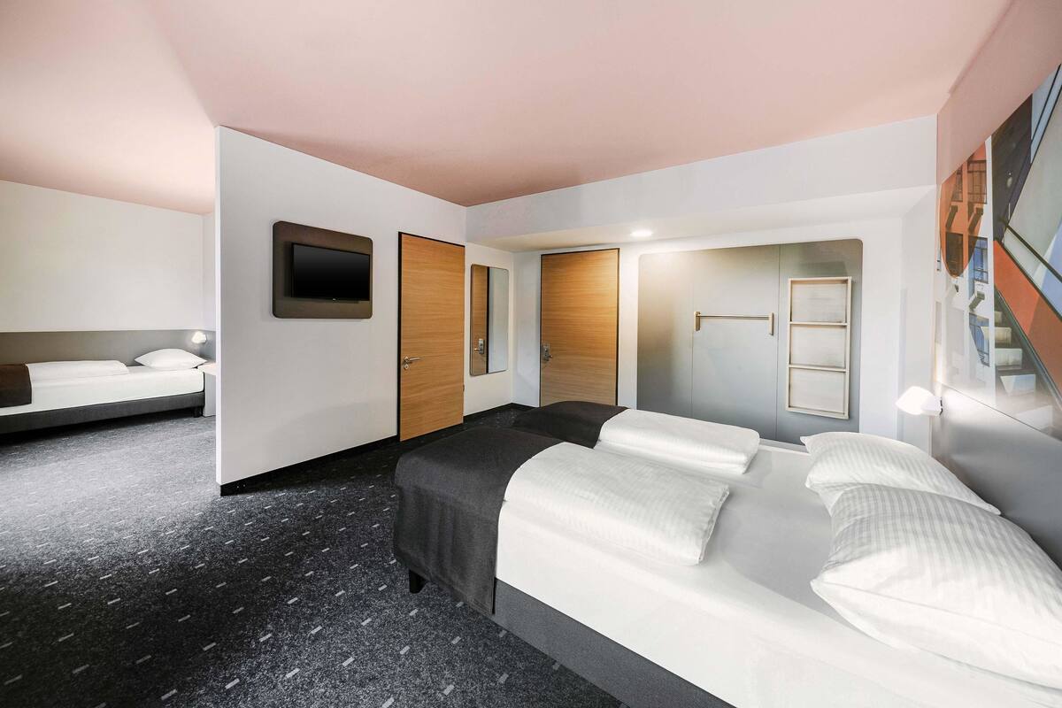 Una habitación de hotel con cama, escritorio, espejo y armario.