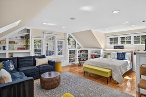 Amplio dormitorio tipo loft con una cama grande, un sofá y un rincón de lectura con estanterías.