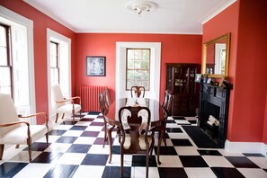 A dining room with a checkered floor, a central table, and chairs.