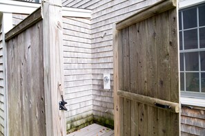 A wooden exterior with a door and window, a metal latch, and a small step leading to a lower level.