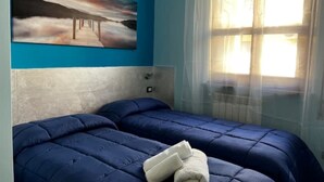 Ein Schlafzimmer mit einem Bett, einem Bild an der Wand und einem Fenster mit Vorhängen.